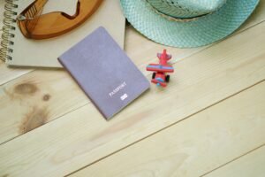 Travel essentials including a passport, notebook and toy airplane laid out on a table