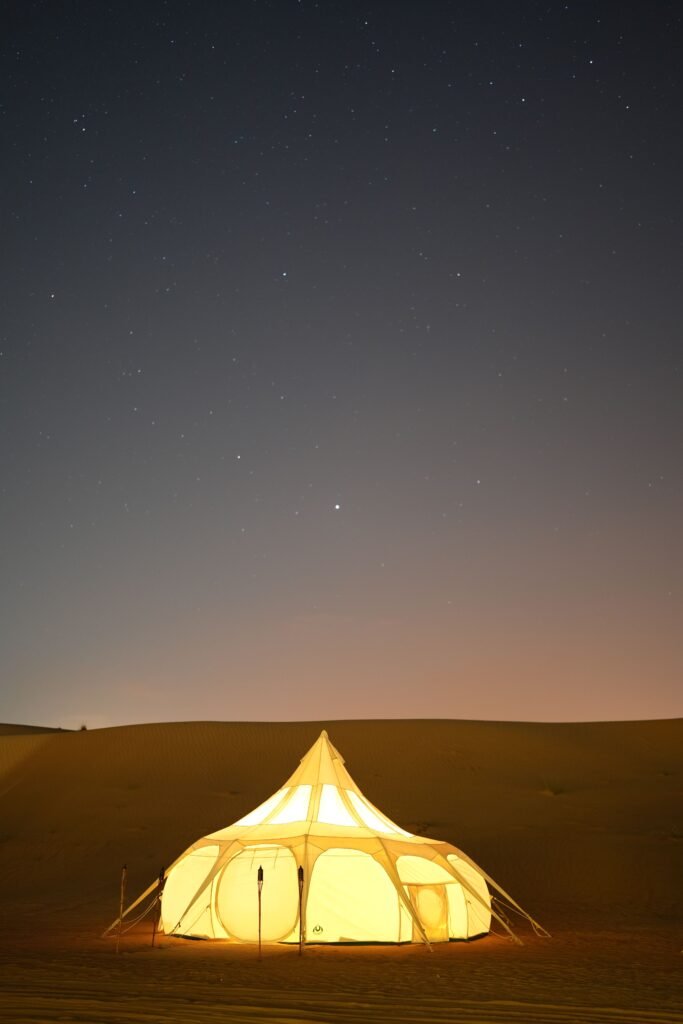 Glowing glamping tent against a starry night sky in the desert